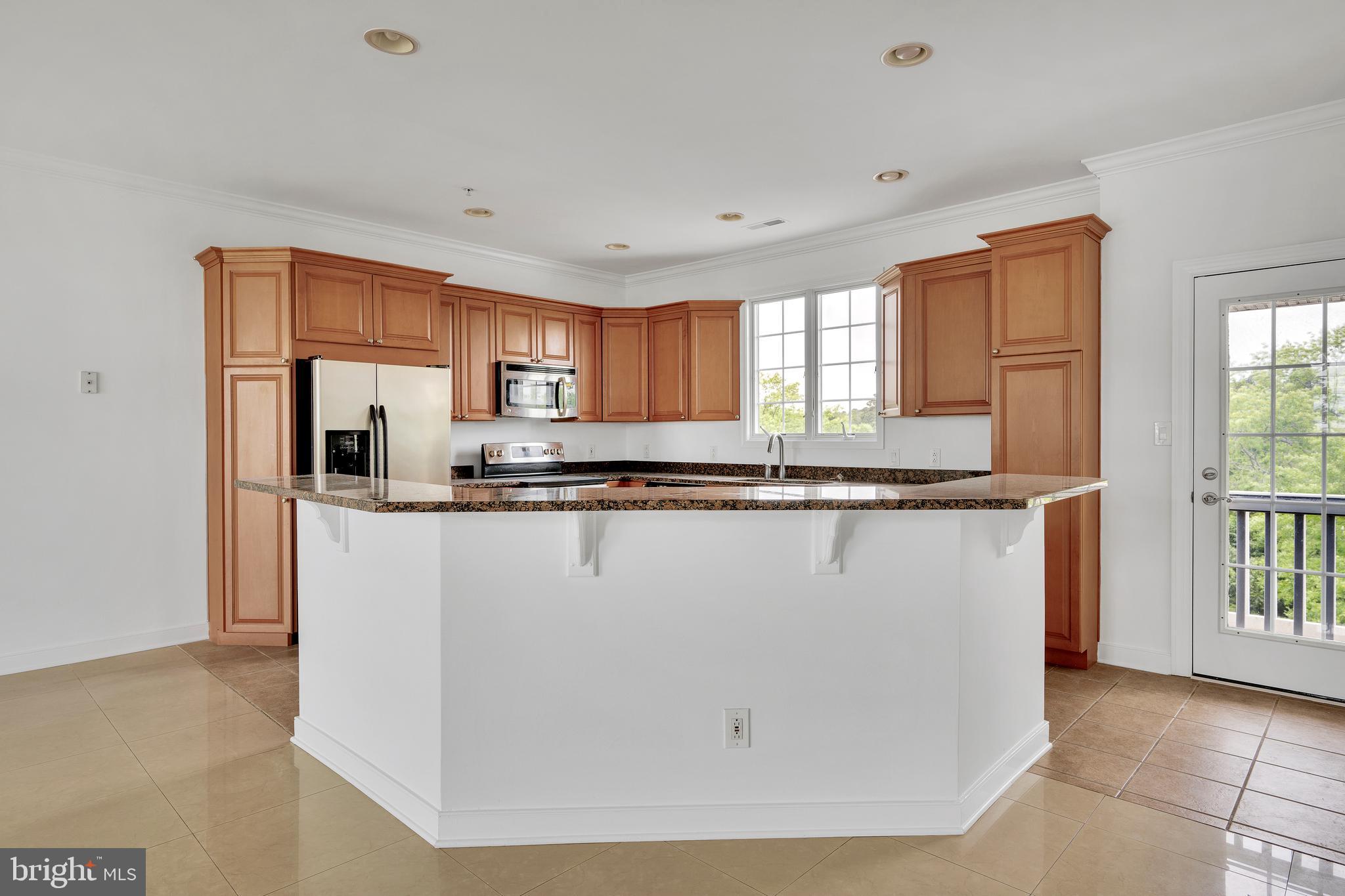 9823 Golf Course Road, Unit 16 Ocean City, MD 21842 - Photo 9 of 33 a kitchen with granite countertop a refrigerator a stove a sink and a window