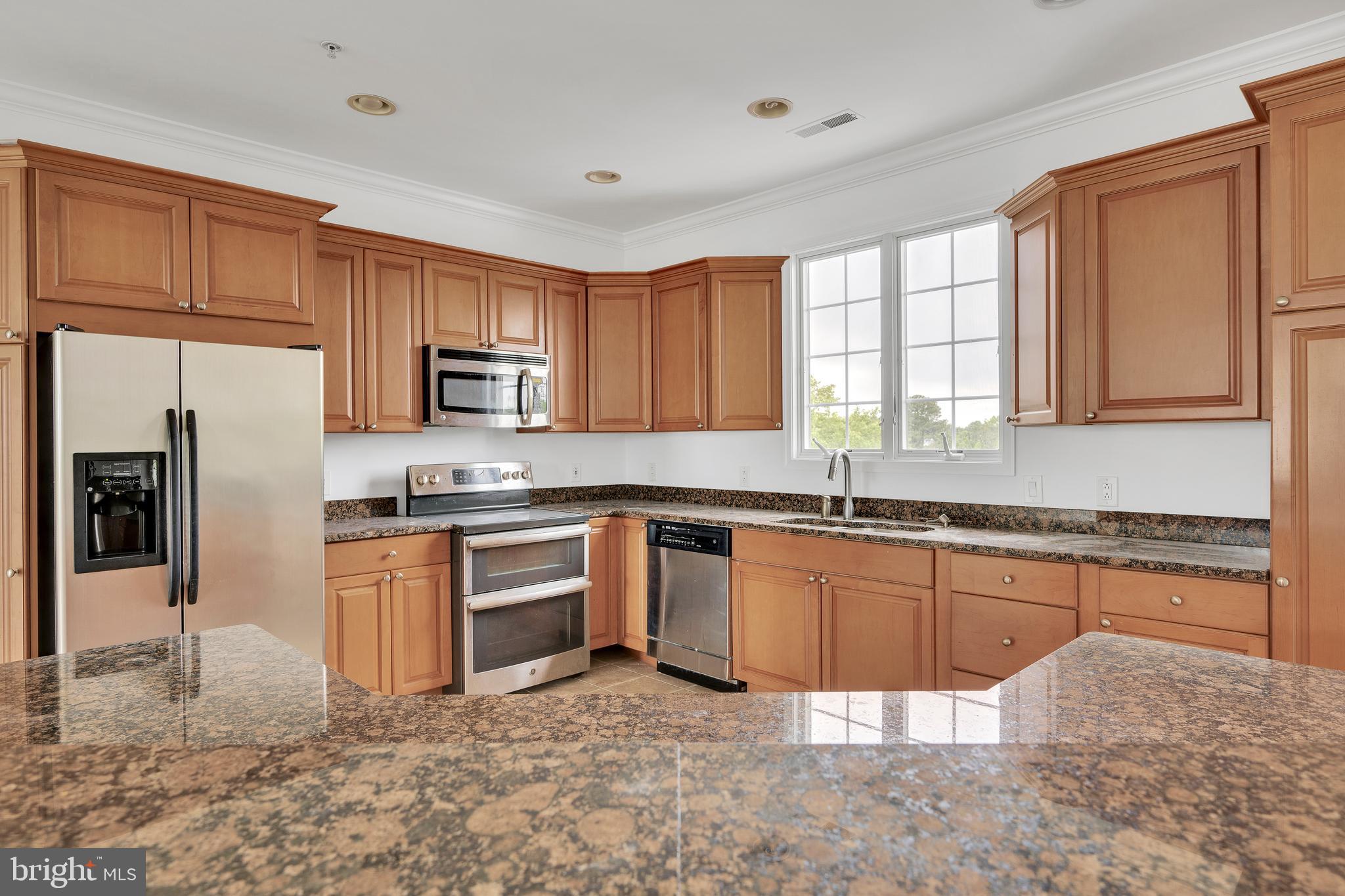 9823 Golf Course Road, Unit 16 Ocean City, MD 21842 - Photo 10 of 33 a kitchen with stainless steel appliances granite countertop a refrigerator sink stove microwave and cabinets