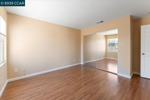 an empty room with wooden floor & windows