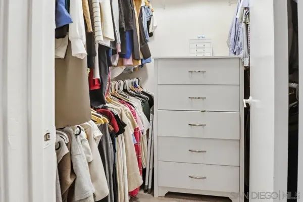 a view of walk in closet with clothes and shoes