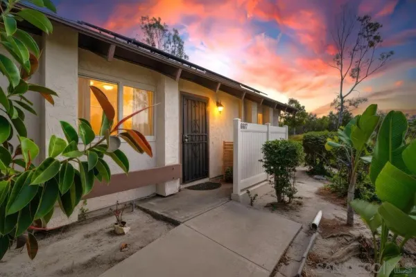 a backyard of a house with table and chairs with potted plants