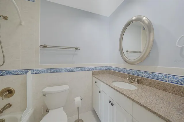 a bathroom with a granite countertop toilet sink and mirror