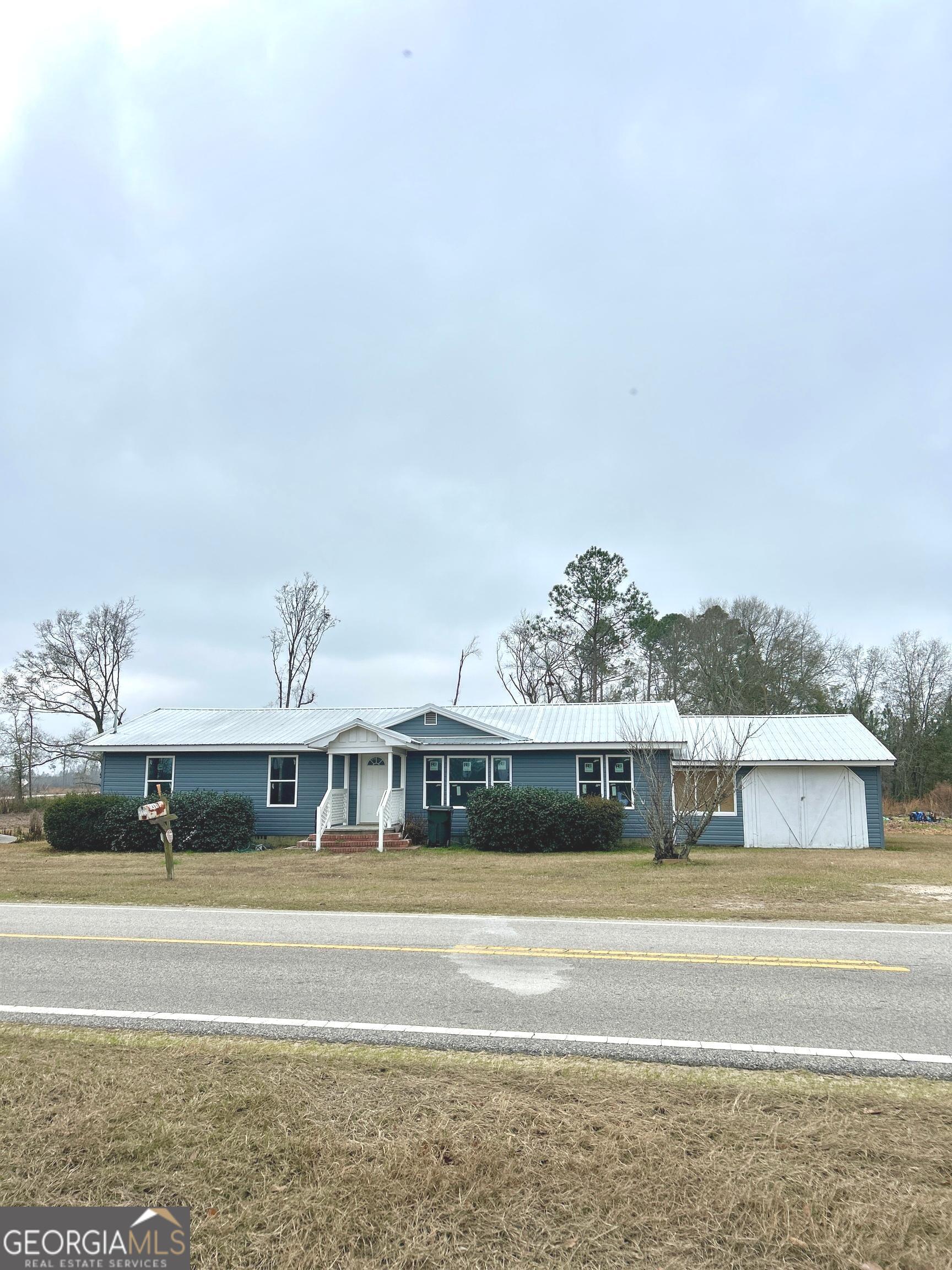 a view of a big house with a big yard and large trees