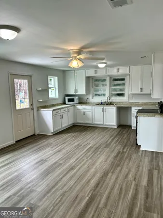 a large kitchen with kitchen island granite countertop wooden floors and white cabinets