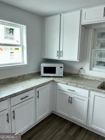 a kitchen with granite countertop white cabinets and a sink