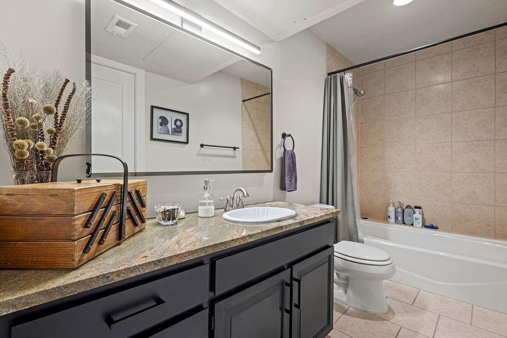 9222 Church Road, Unit 117 Dallas, TX 75231 - Photo 19 of 24 a bathroom with a granite countertop sink a toilet and a bathtub