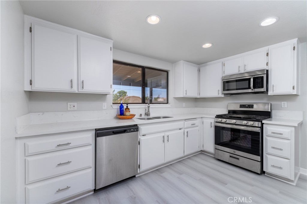 a kitchen with granite countertop white cabinets stainless steel appliances and a sink