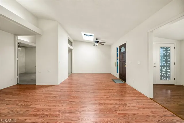 a view of an empty room with window and wooden floor
