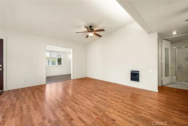 a view of an empty room with a kitchen and a ceiling fan
