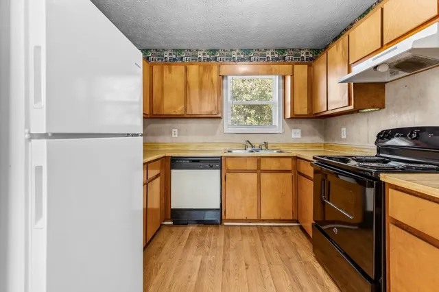 a kitchen with stainless steel appliances granite countertop wooden cabinets sink and a stove