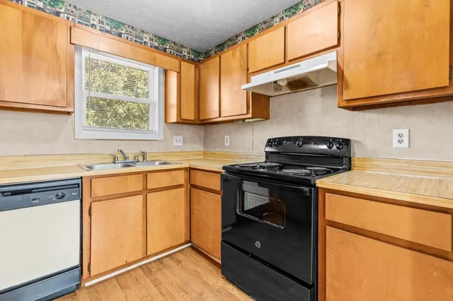 a kitchen with stainless steel appliances granite countertop cabinets sink and a window