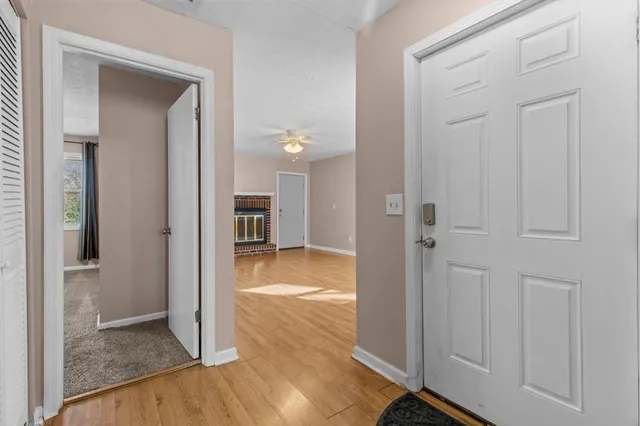 a view of an empty room with wooden floor fireplace and a window