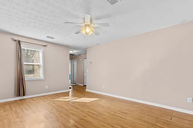 an empty room with wooden floor and windows