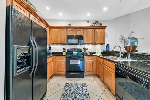 a kitchen with stainless steel appliances granite countertop a refrigerator a stove and a sink
