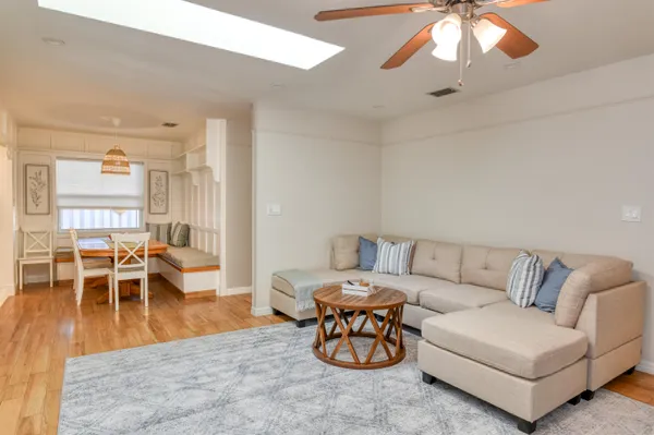 a living room with furniture and a dining table with wooden floor