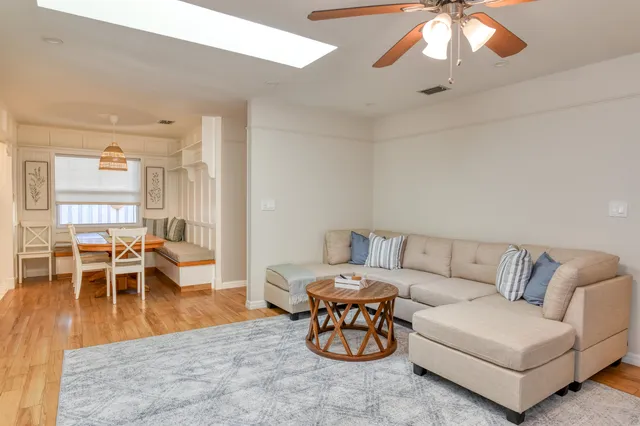 a living room with furniture and a dining table with wooden floor