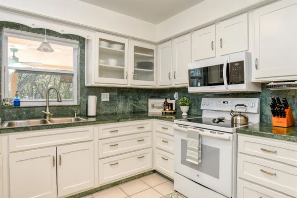 a kitchen with granite countertop white cabinets and white appliances