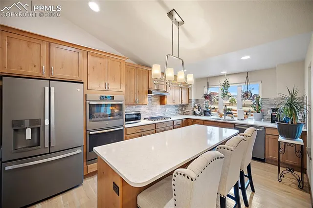 a kitchen with stainless steel appliances granite countertop a refrigerator a sink dishwasher a stove and a refrigerator