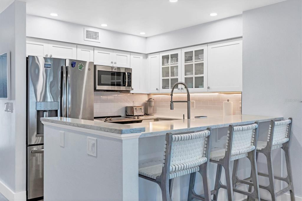 420 Gulf Boulevard, Unit 20 Boca Grande, FL 33921 - Photo 11 of 44 a kitchen with kitchen island a counter top space cabinets and stainless steel appliances