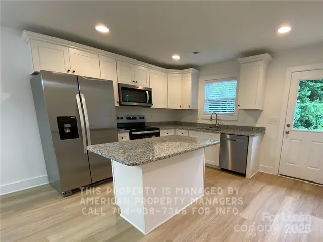 a kitchen with stainless steel appliances granite countertop a sink stove refrigerator and microwave