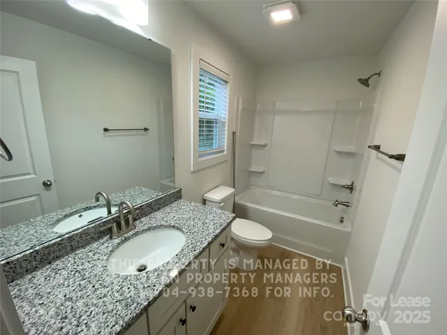 a bathroom with a granite countertop sink mirror vanity and a bathtub