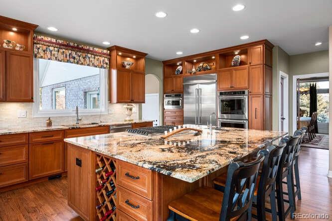 71 North Ranch Road Littleton, CO 80127 - Photo 4 of 40 a kitchen with kitchen island granite countertop a table chairs sink and cabinets