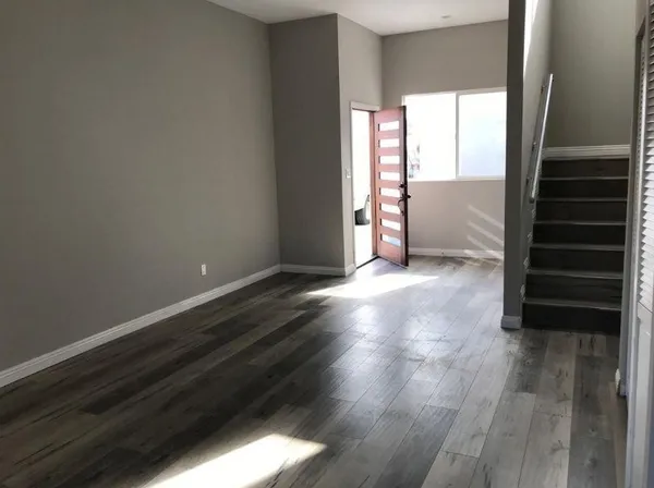 an empty room with wooden floor closet and windows
