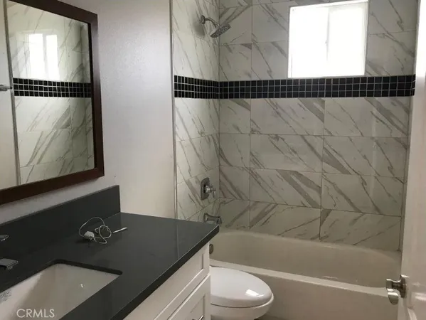a bathroom with a granite countertop sink and a bathtub