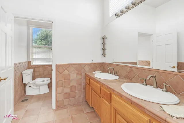 a bathroom with a double vanity sink mirror and toilet