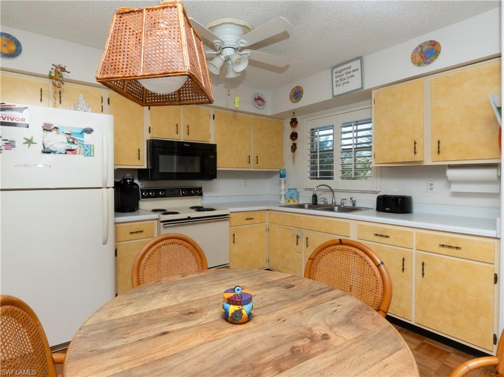 3325 Airport Road North, Unit E8 Naples, FL 34105 - Photo 5 of 7 a kitchen with stainless steel appliances granite countertop a sink a stove a refrigerator cabinets and a dining table