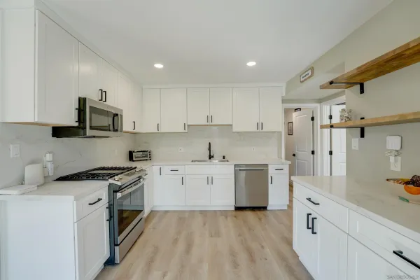 a kitchen with white cabinets and appliances