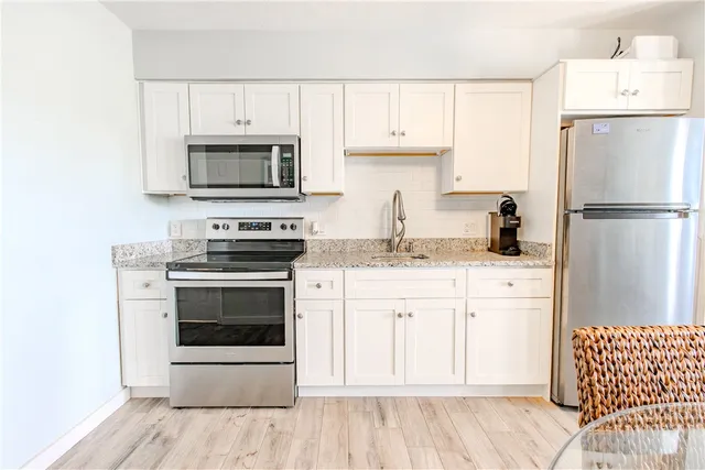 a kitchen with granite countertop a sink stainless steel appliances and white cabinets