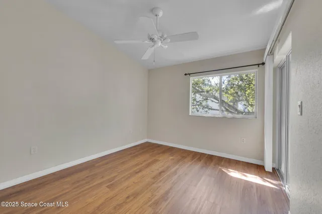 an empty room with wooden floor fan and windows