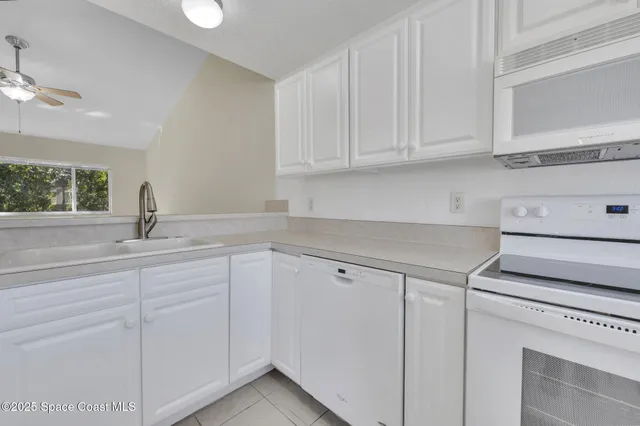 a kitchen with white cabinets and sink