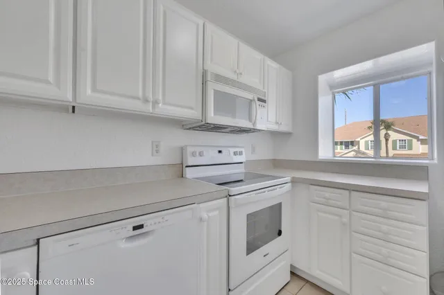 a kitchen with white cabinets and white appliances