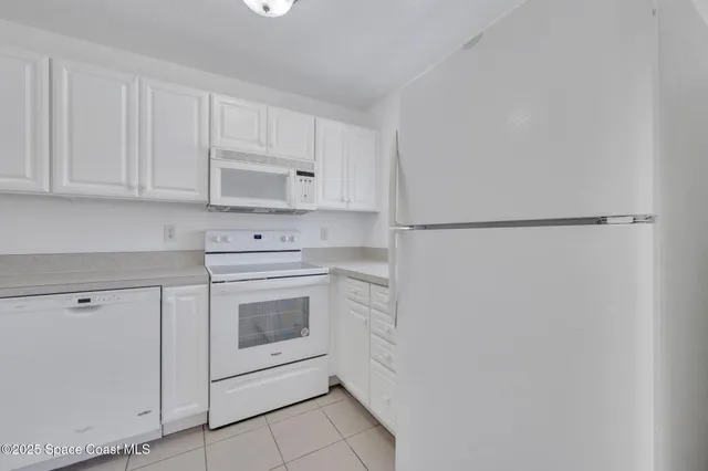 a kitchen with white cabinets and white appliances