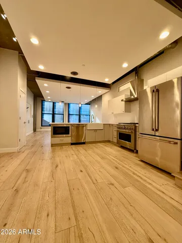 a view of kitchen with stainless steel appliances wooden floor and living room view