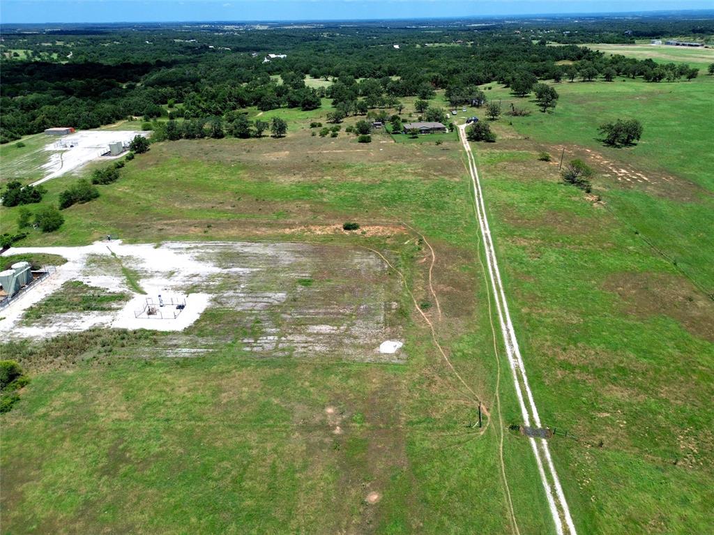 2186 Gilliland Road Springtown, TX 76082 - Photo 20 of 25 Expansive rural landscape featuring a long private driveway, a single-story residence, and various outbuildings