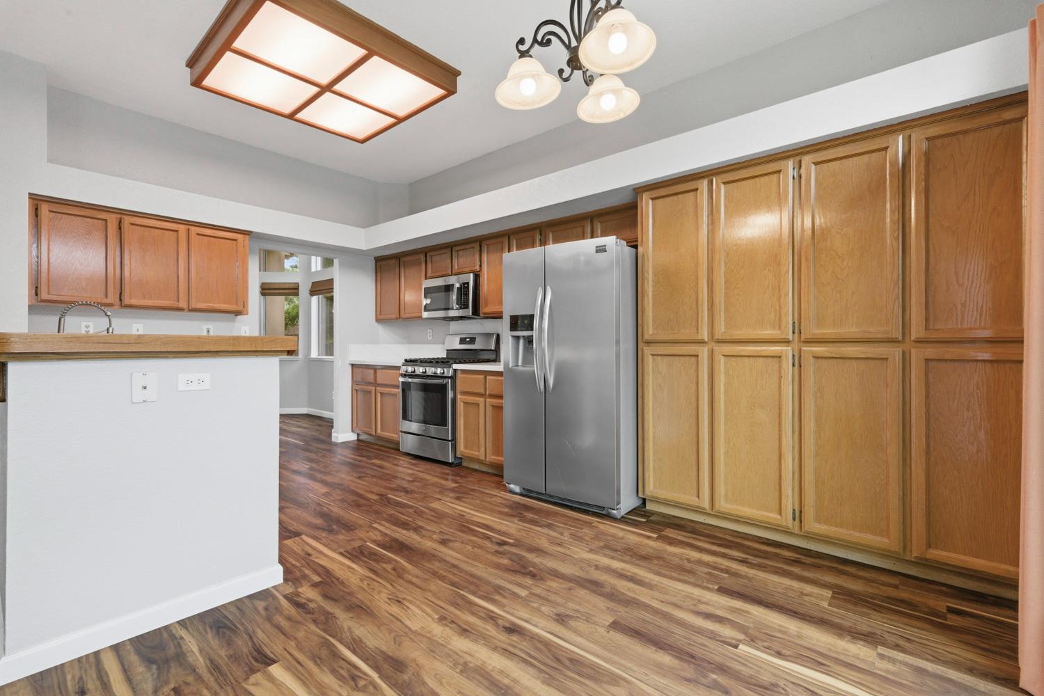 969 Colson Way Galt, CA 95632 - Photo 14 of 38 a kitchen with stainless steel appliances granite countertop a refrigerator a oven a sink with wooden floors and cabinets