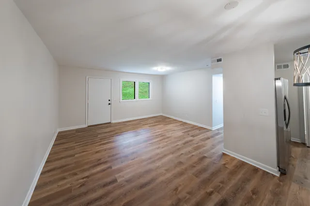 an empty room with wooden floor and window