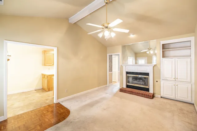 a view of a livingroom with a fireplace a ceiling fan and wooden floor