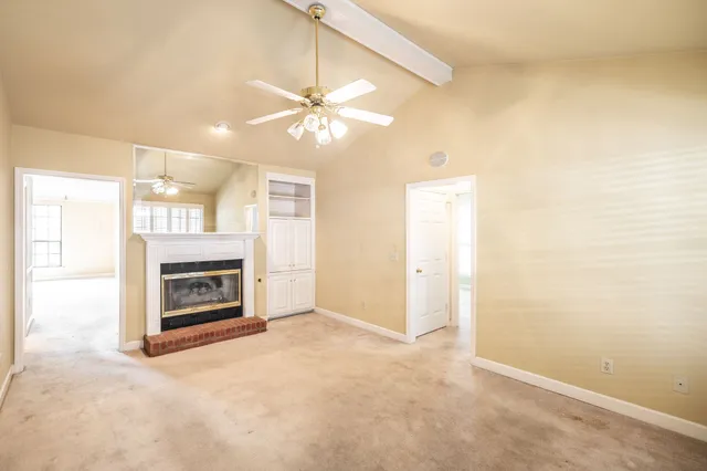 an empty room with windows fireplace and fan