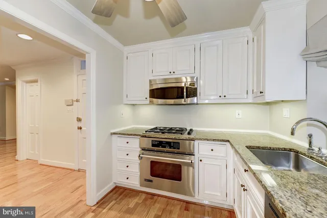 a kitchen with cabinets stainless steel appliances and wooden floor