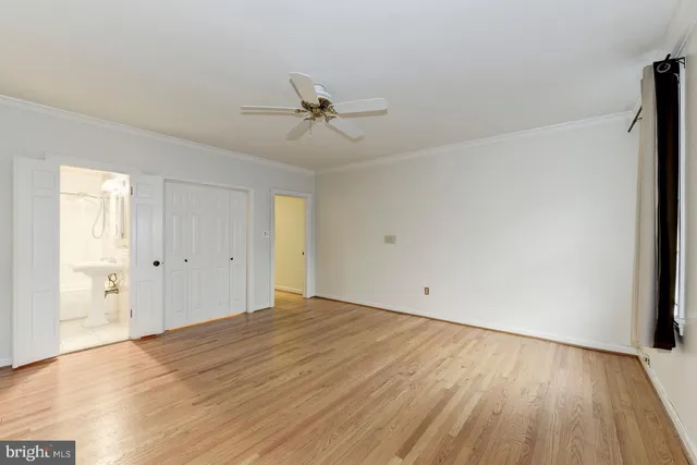 a view of empty room with wooden floor and fan