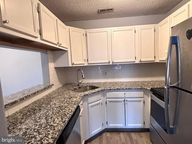 a kitchen with granite countertop a sink stainless steel appliances and cabinets
