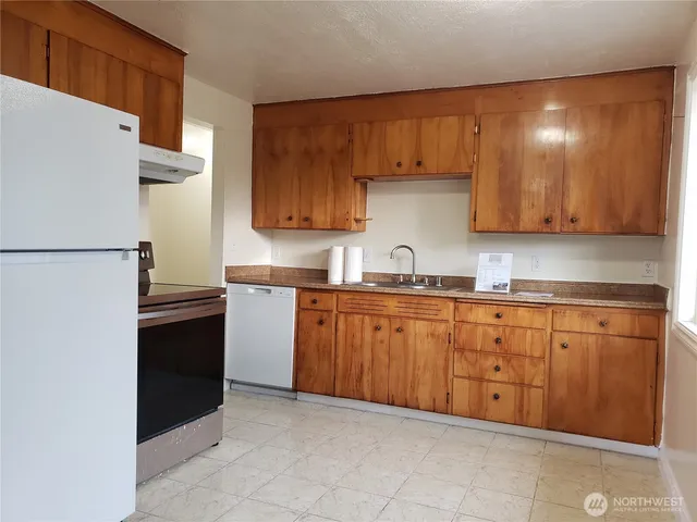 a kitchen with granite countertop a refrigerator sink and cabinets