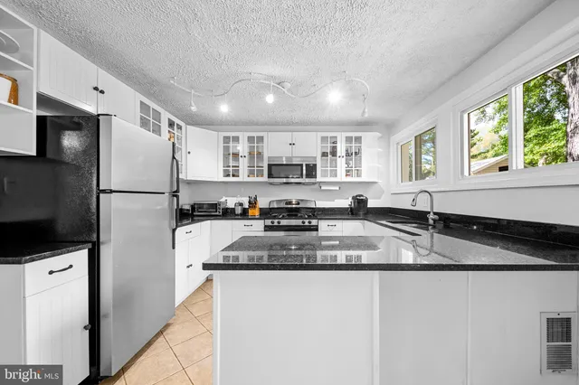 a kitchen with kitchen island granite countertop a sink cabinets and window