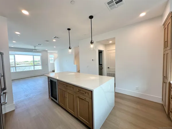 a large kitchen with kitchen island a stove a sink a refrigerator and wooden floor