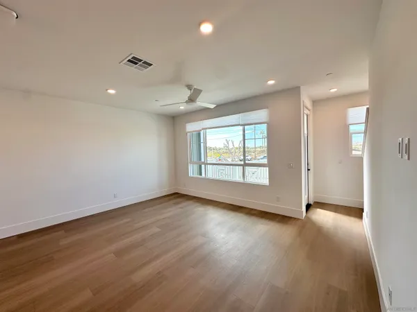 an empty room with wooden floor and windows