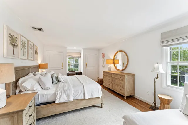 a bedroom with a bed a dresser with mirror and window